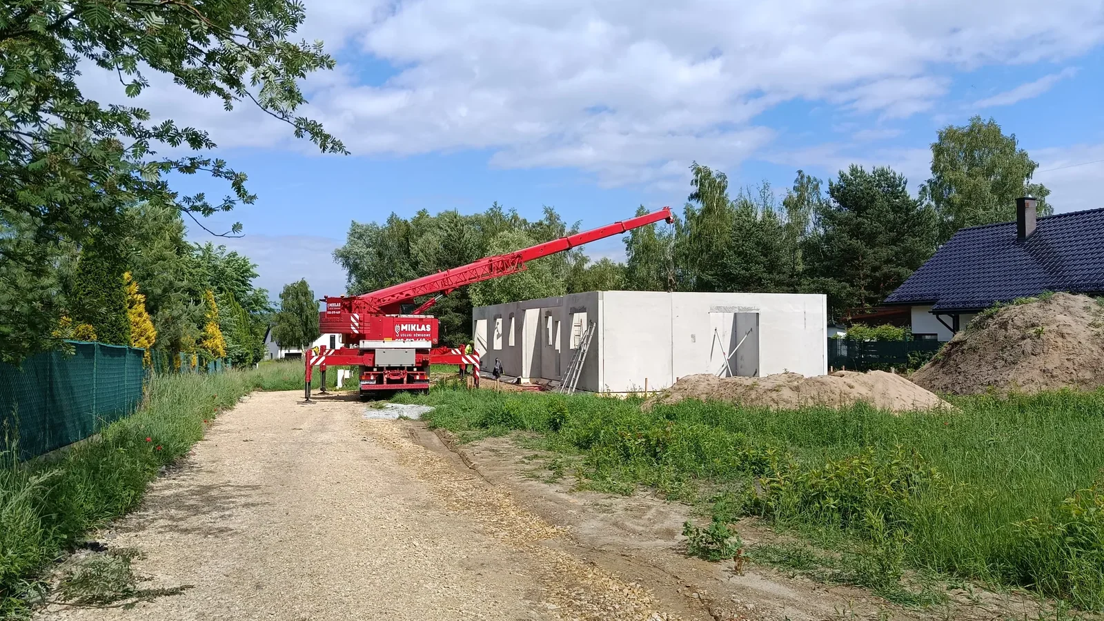 Droga dojazdowa do działki budowlanej z ustawionym żurawiem